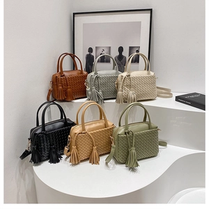 Detail of hand-woven PU leather handbags in six colors with tassels on a display stand