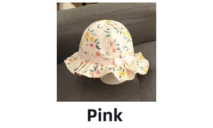 Detail of pink cotton baby sun hat with floral pattern, ruffle brim and bow decoration