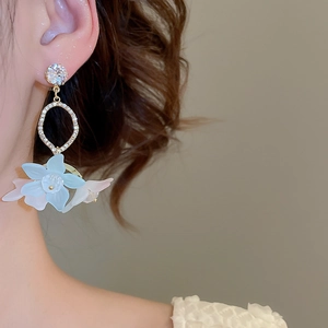 Close-up of floral drop earrings with blue and white petals and sparkling zircons