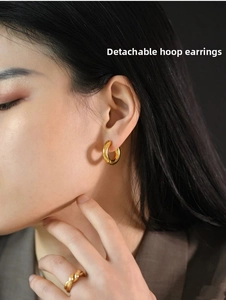 Close-up of detachable gold hoop earrings and matching woven ring on a model