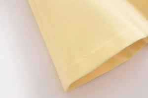 Macro detail of the soft yellow fabric with fine stitching and plain weave texture