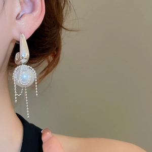 Detail of silver bow pearl earrings with long bead chain tassels on a model