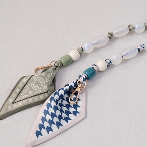 Detail of luxury bag strap charms with resin beads and printed silk scarf ribbons