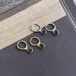 Detailed close-up of gold and silver S925 hoops with green zircon gemstone charms