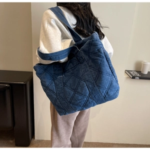 Détail du sac cabas en denim bleu foncé avec motif en losanges sur le dos du modèle