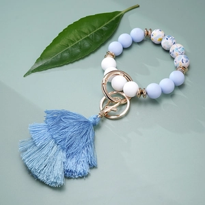 Detail of blue silicone bead keychain bracelet with triple-layered tassel and gold clasp