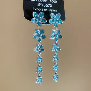 Close-up of S925 silver dangling earrings with five blue zircon flowers and tassels
