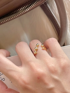 Detailed close-up of golden liquid metal irregular open ring with high-polished texture