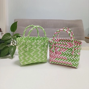 Detail of hand-woven basket bags in green, white, and pink patterns with polished texture