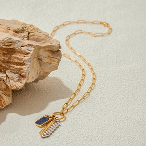 Detailed view of 18K gold chain with lapis lazuli and mixed metal feather pendants