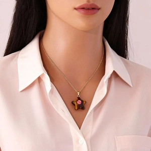 Star-shaped tiger eye stone pendant on a gold necklace worn by a female model