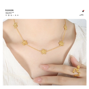 Detail of gold floral necklace and heart ring set worn by model in minimalist fashion style