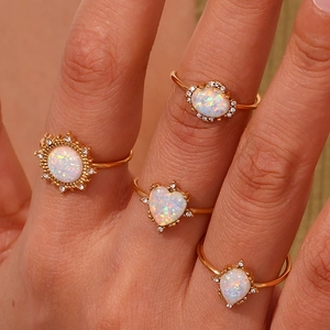 Close-up of four gold adjustable rings with teardrop and heart-shaped opal stones