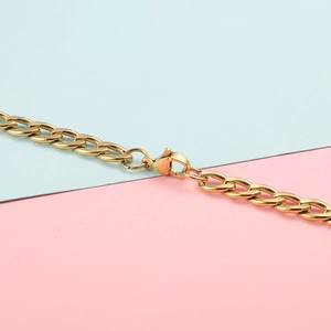 Detail of a golden Cuban link chain necklace featuring a polished metal lobster clasp