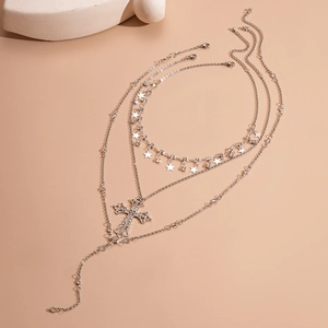 Detail of layered silver necklace with cross and star pendants featuring rhinestone accents