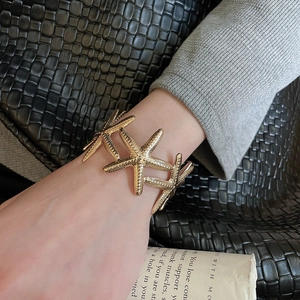 Detailed view of golden starfish cuff bracelet with textured grain on model wrist