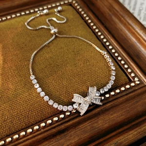 Close-up of adjustable silver zircon bow bracelet on green velvet background