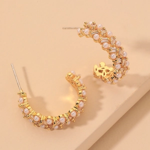 Detail shot of gold C-shaped earrings with pearls and S925 silver hallmark engraving