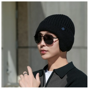 Close-up of black ribbed knit winter hat with earflaps and a metallic side logo