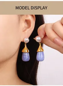 Detail view of pearl and purple resin teardrop earring worn by a model in soft lighting