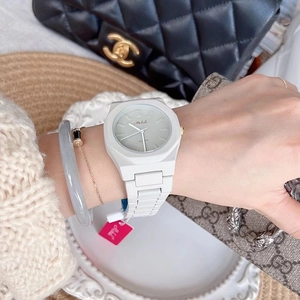 Close-up of a white luxury women's watch with golden dial accents on a model wrist