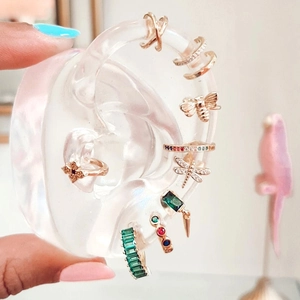 Detailed view of layered gold hoop earrings with colorful zircon and insect charms