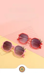 Close-up of octagon children sunglasses with metal bow tie accents in pink and red