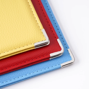 Stack of yellow, red and blue PU leather passport covers with silver metal corner protectors