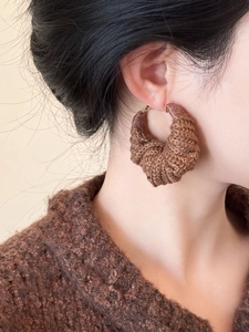Gros plan de créoles en crochet marron foncé avec texture tricotée main sur mannequin