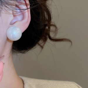 Side view of large round white pearl stud earring on model for an elegant French style