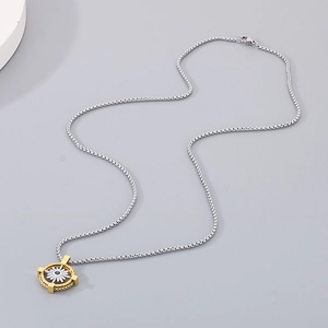 Detail of silver box chain with gold and silver compass star pendant on gray background