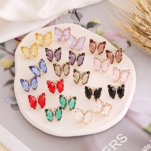 Flat lay of colorful butterfly earrings with crystal stones on a white stone background