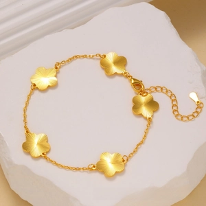 Detail view of gold clover flower bracelet with radial brushed texture and adjustable clasp