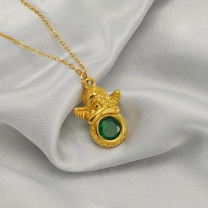 Detail of a vintage golden Cupid angel pendant with a large green gemstone inlay