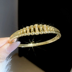 Close-up of 18k gold plated bangle featuring hollow wavy design and shimmering zircons