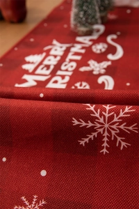 Close-up of red plaid Christmas table runner with snowflakes and Merry Christmas print