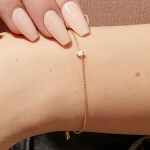 Detailaufnahme eines zarten Armbands aus S925 Silber in Gold mit einem weißen Opalstein