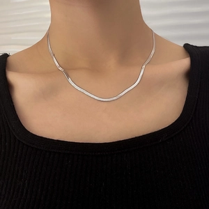 Close-up of minimalist silver snake chain necklace on a model wearing black knitwear