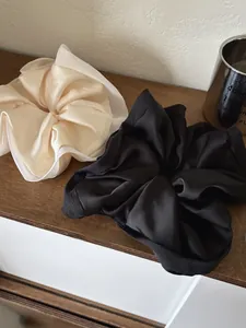 Close-up of set of 2 premium satin scrunchies in beige and black with soft silk texture