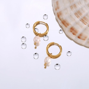 Close-up of 18K gold plated hoop earrings with natural freshwater pearls on reflective surface