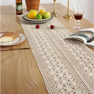 Detail of beige rectangular hand-woven table runner with hollow patterns and tassels