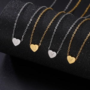 Close-up of heart-shaped letter pendants in gold and silver finish on a dark texture