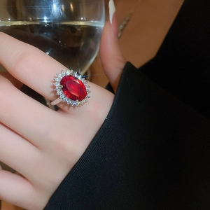 Close-up of a silver ring with an oval red gemstone and zircon halo on model hand