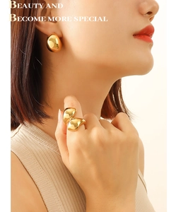Close-up of chunky gold C-shape earrings and matching ring with mirror finish