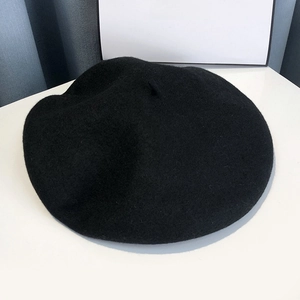 Detail of a classic black wool beret with soft felt texture and French style top stalk