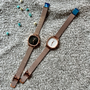 Rose gold square watches with mesh bands in black and white dials on soft grey background