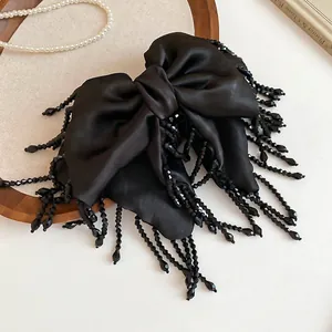 Pince à cheveux élégante à nœud en satin noir avec glands perlés sur plateau
