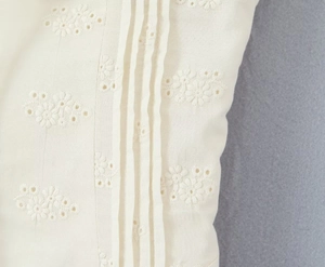 Detail of cream puff sleeve dress with floral embroidery and vertical pleats