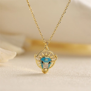 Close-up of golden necklace with blue enamel bull head pendant and small sparkling crystals