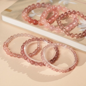 Detailed view of pink strawberry quartz beaded bracelets on a display stand
